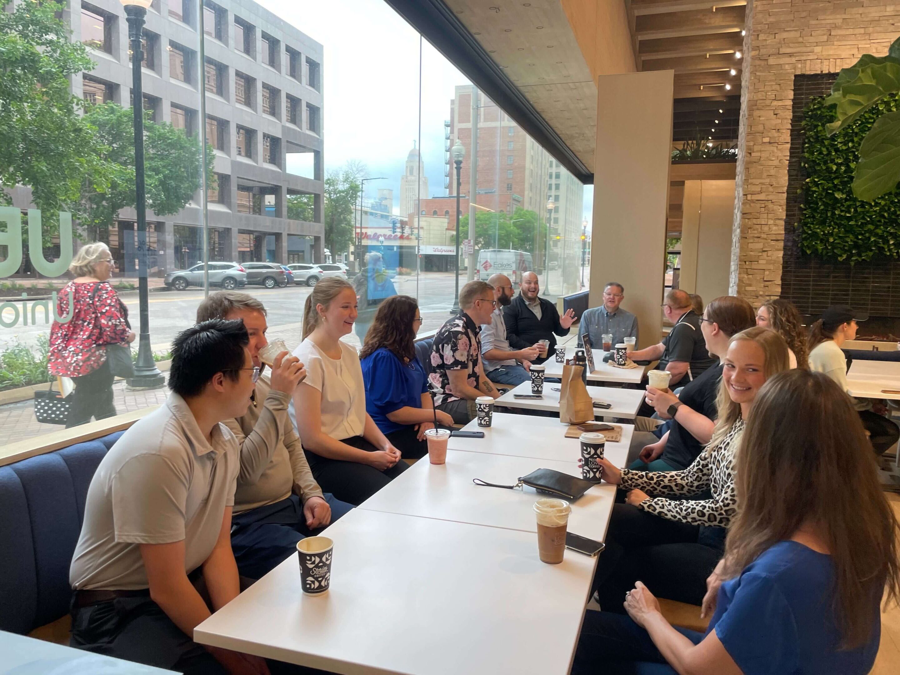 group of people sitting at long table, enjoying coffee and chatting